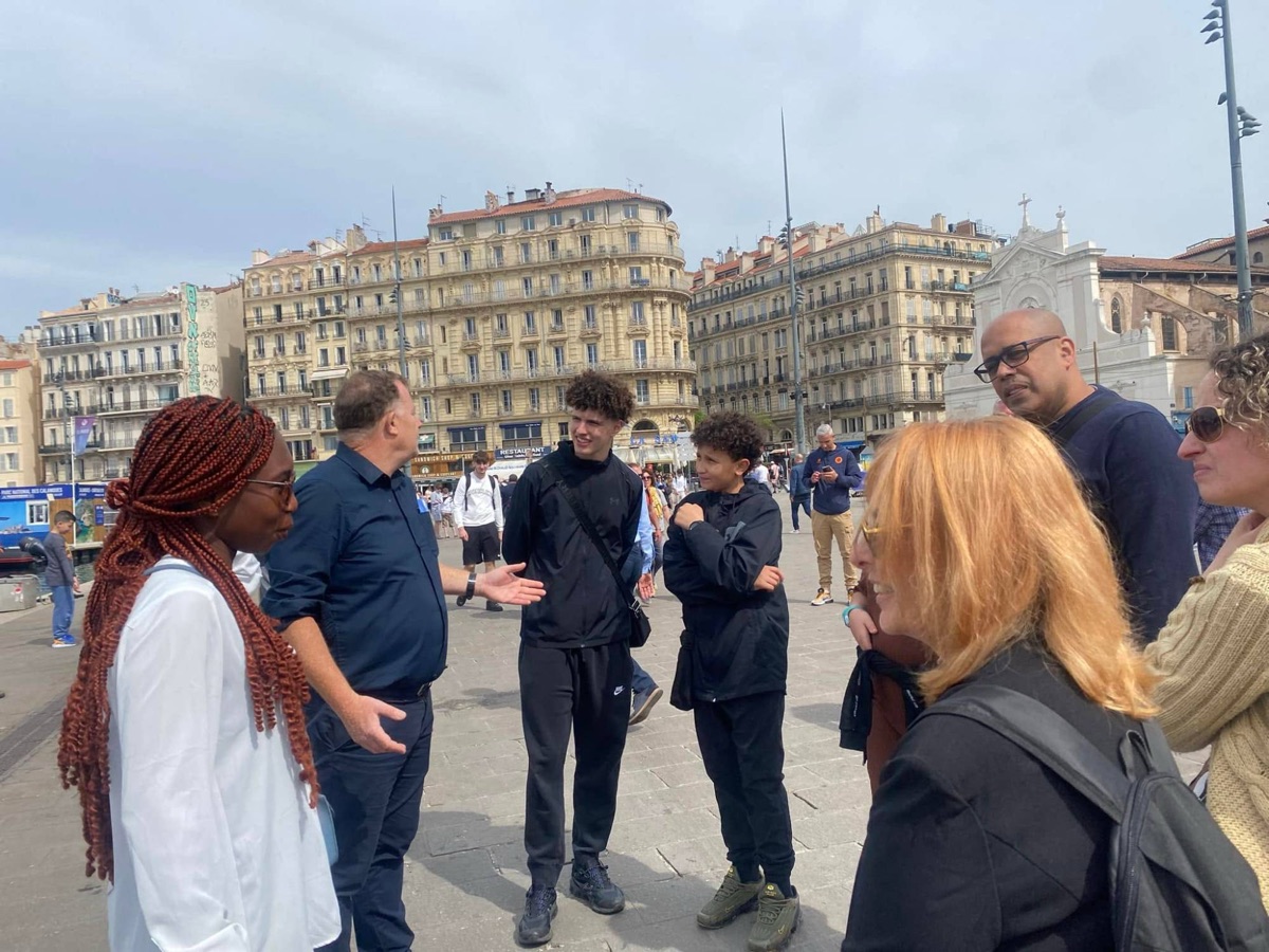 Bio en pleine discussion philosophique avec un groupe de passants sur le Vieux-Port de Marseille.