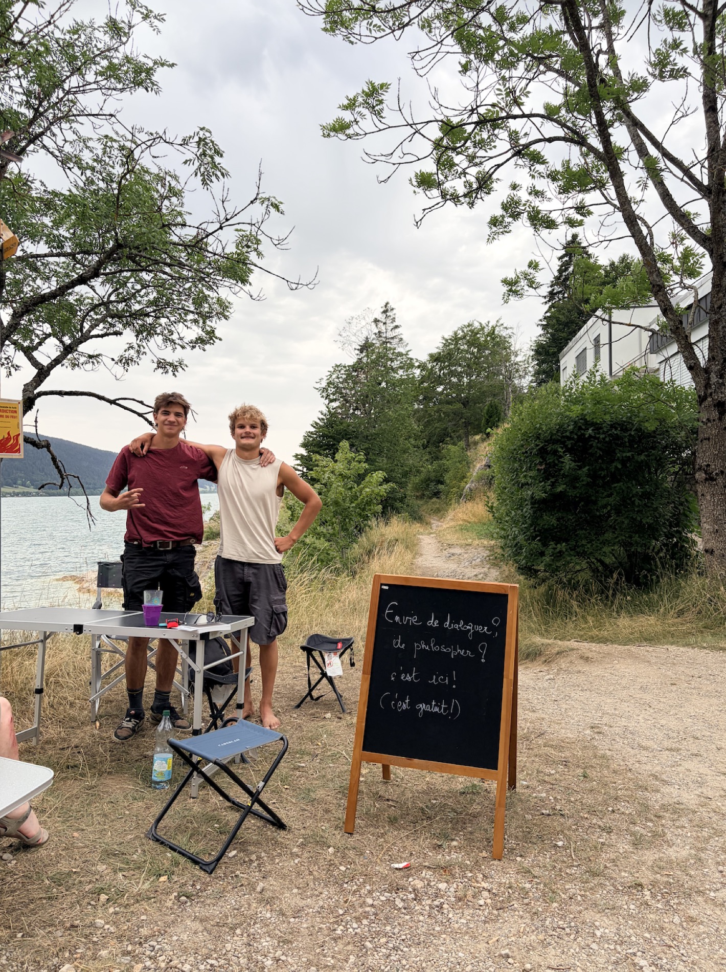 Solal et Amaric, bras dessus bras dessous, au bord du lac de Joux, près de la pancarte.