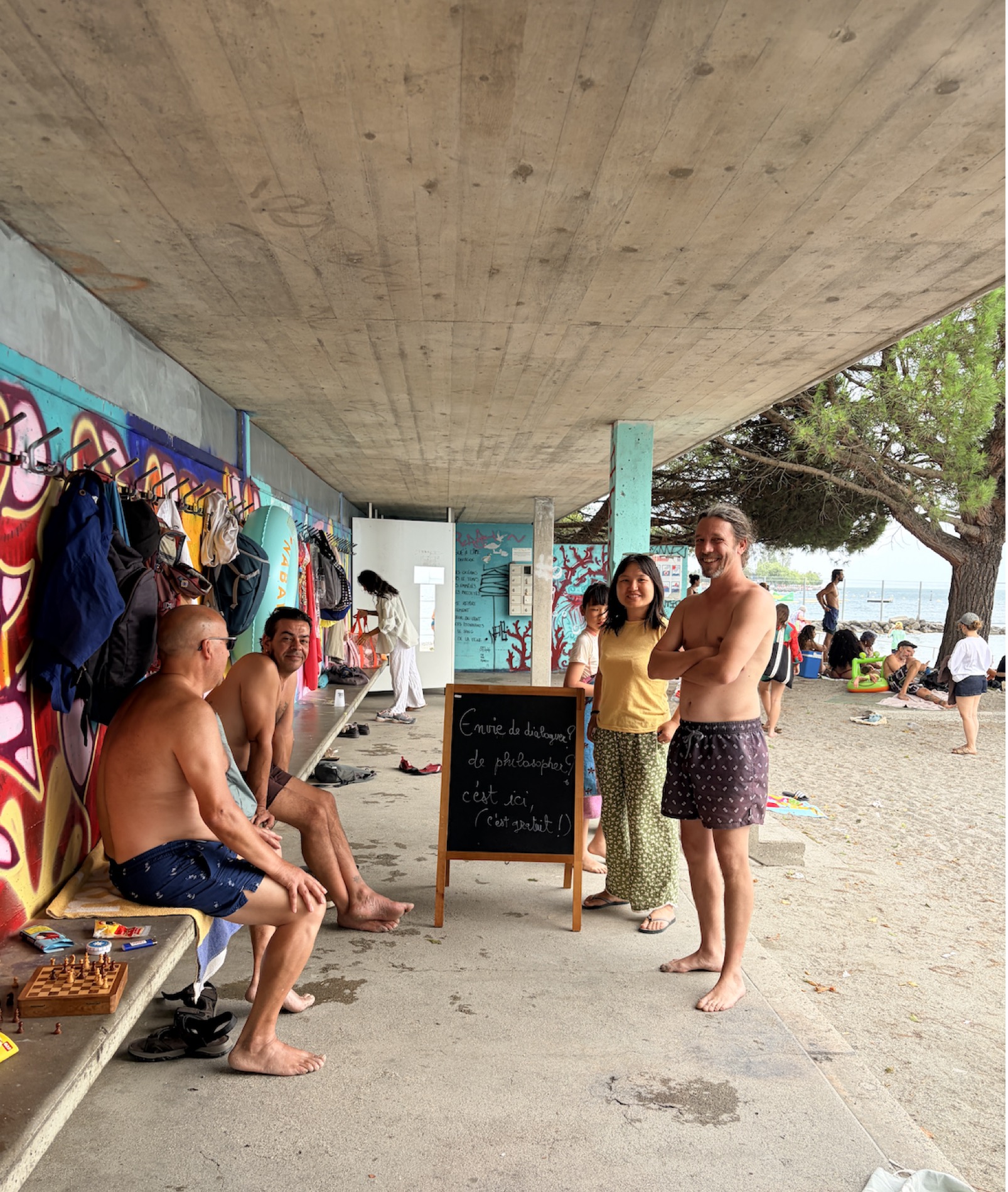 Wei et Maël, sous le pavillon de la plage de Vidy, près de joueurs d’échecs et du lac Léman.