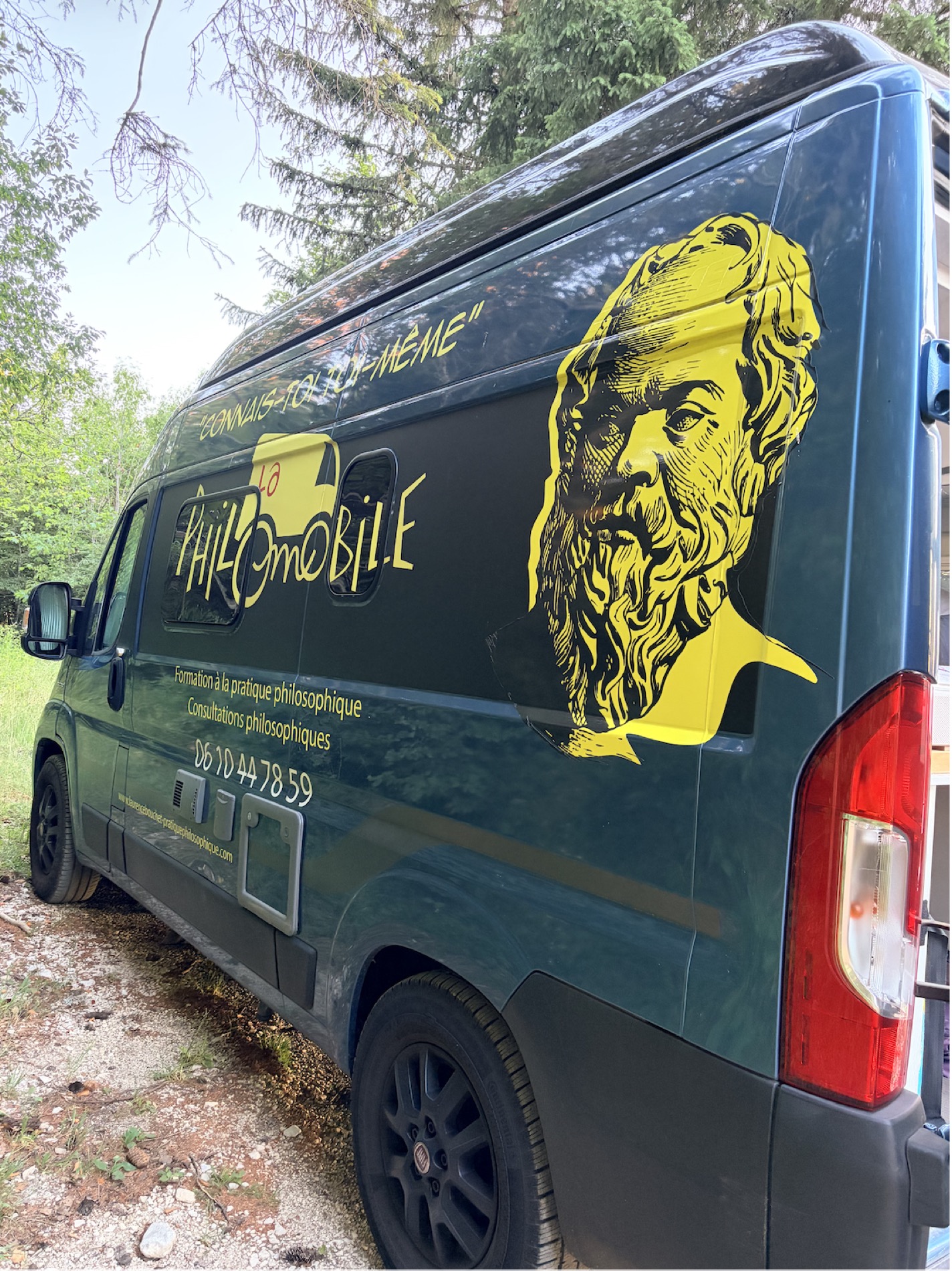 La Philomobile garée en forêt, avec le portrait de Socrate et la devise « Connais-toi toi-même ».