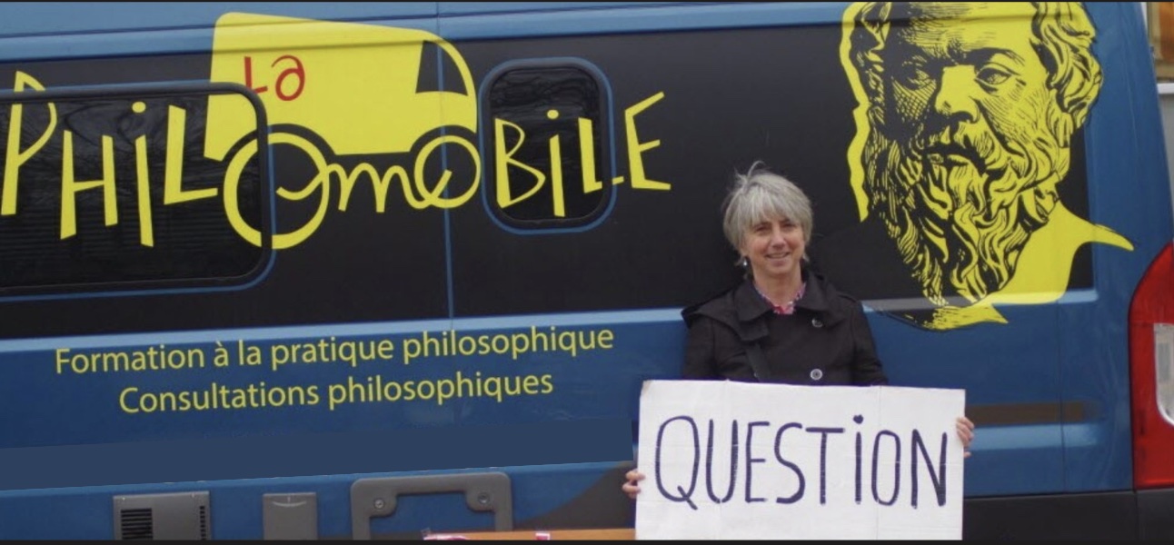 Laurence Bouchet, consultante philosophe, devant la Philomobile avec une pancarte « Question »